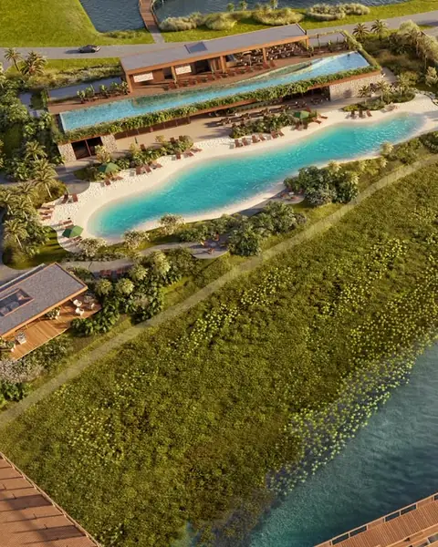 Render visto do alto da praia tropical, com areia clara, água azul-turquesa e espreguiçadeiras, ao lado da piscina